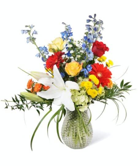 Highlighted by white oriental lilies, blue delphinium and orange spray roses. 
