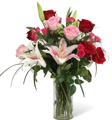 Beautiful glass cylinder vase that is filled with fragrant stargazer lilies and roses. 