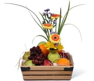 fruit basket with oranges graps and apples and several yellow and purple flowers